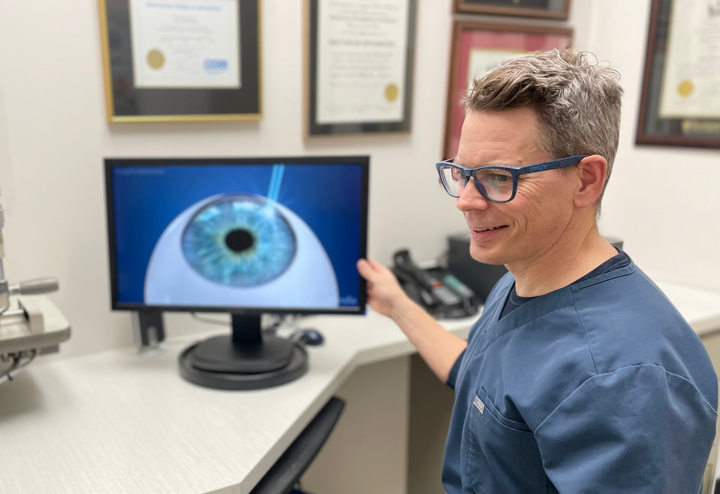 Dr Jeff Sangster with a computer screen showing a simulation of a laser eye surgery.