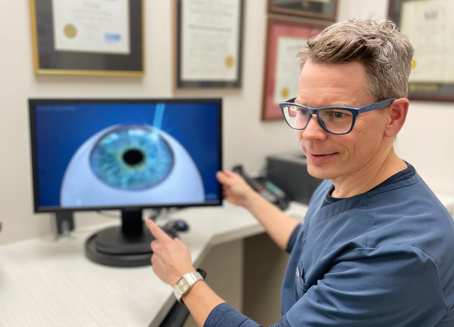 Dr Jeff Sangster pointing to a computer screen showing a simulation of a laser eye surgery.