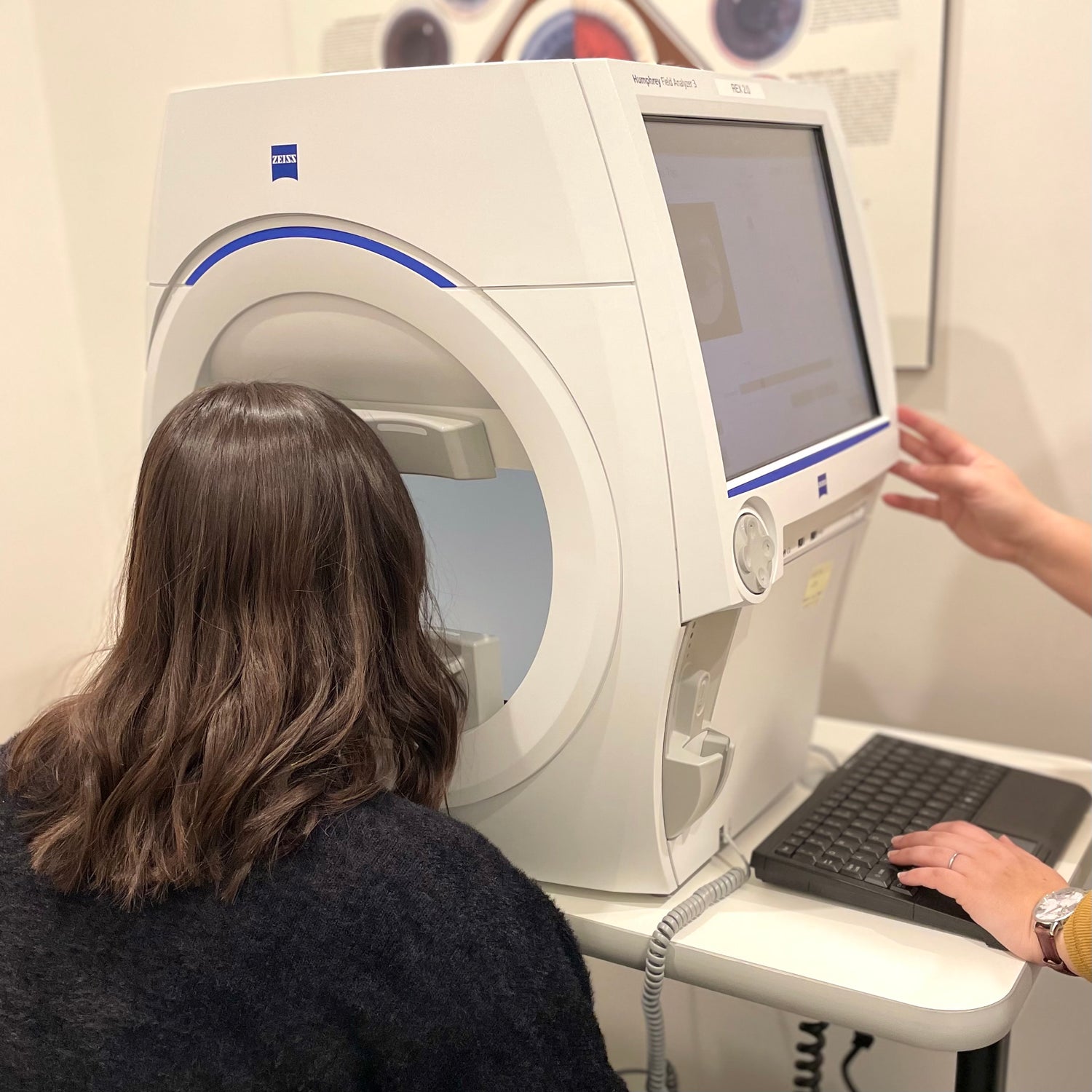 Patient taking a Humphrey Field test. She's leaned forward looking into the machine at a large white screen.