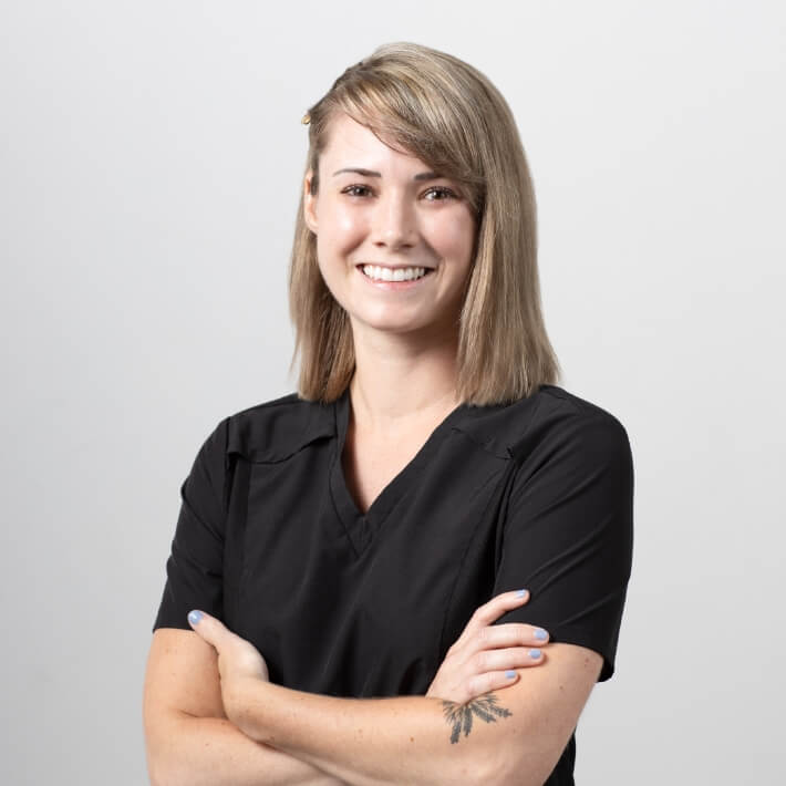 Dr Kelsey Bonang in scrubs, arms folded, smiling.