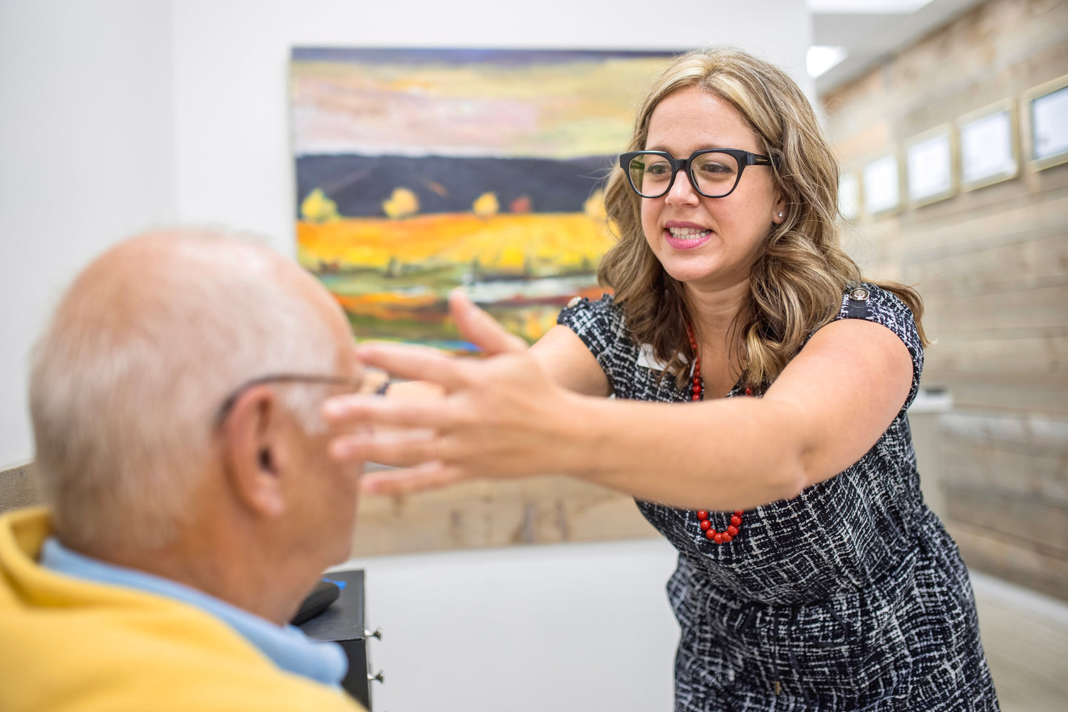 Optician Melanie Mathews is fitting an elderly patient with glasses.