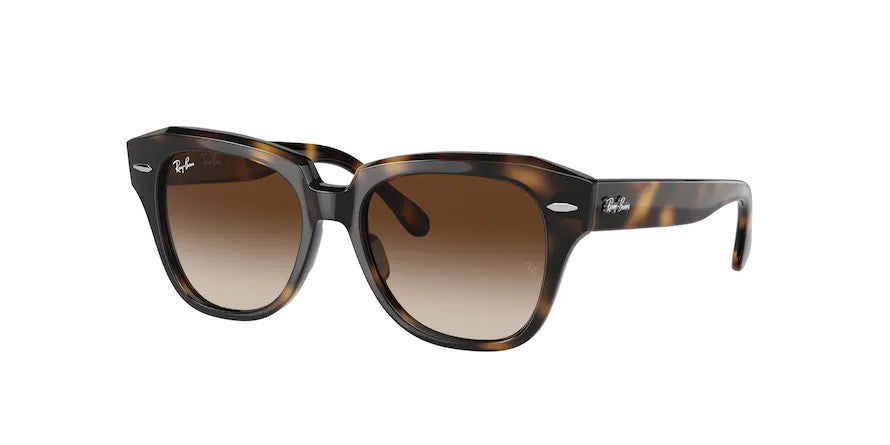 Teen’s unisex sunglasses: A side view of the State Street JR model. The polished Havana frame is made of injected material and has brown gradient lenses. The Ray-Ban logo is located on the temples by the hinges and on one lens.
